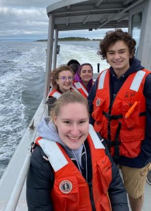 学生 smile while wearing lifejackets on a U N E boat