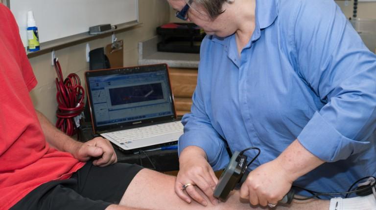 Professor Rudolph using a lab tool on a patient's knee